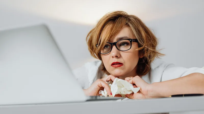 Tired business owner resting her chin on her hands at a laptop