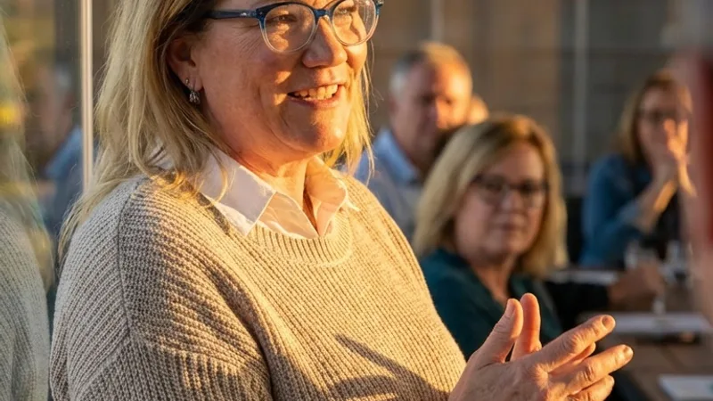 Carol Surbey speaking with a group of business owners in a boardroom at golden hour