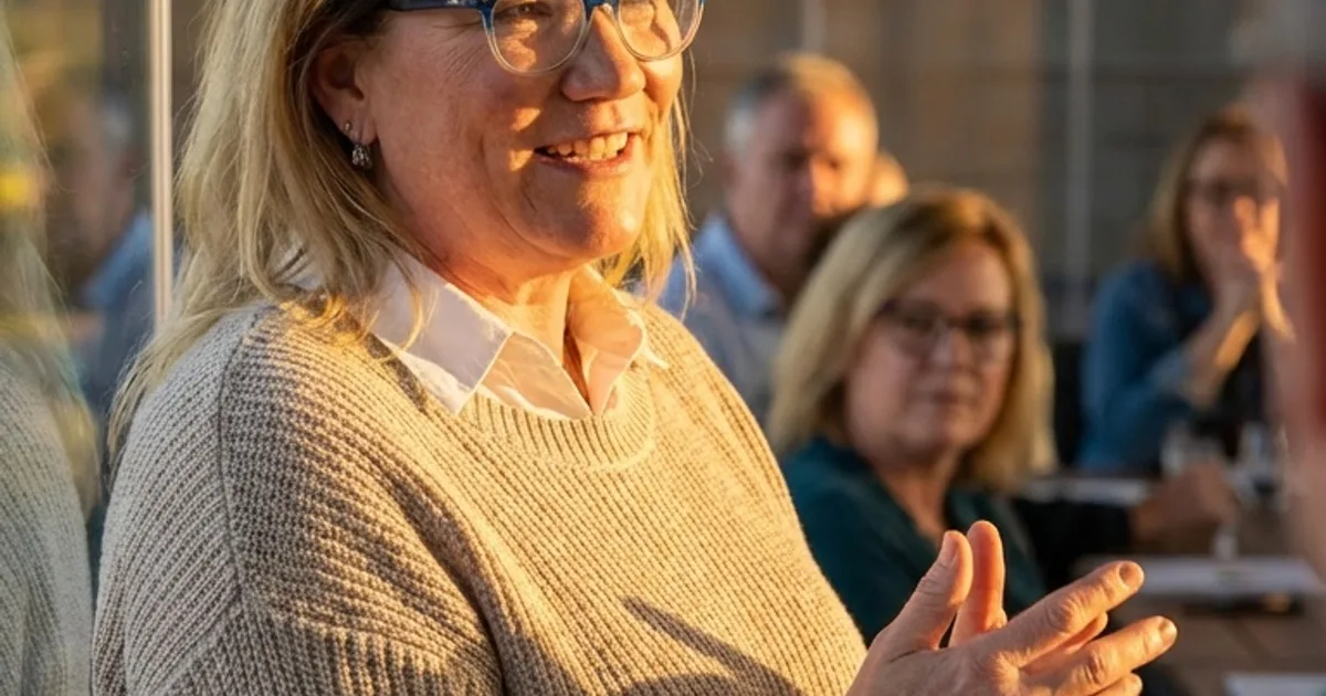 Carol Surbey speaking with a group of business owners in a boardroom at golden hour
