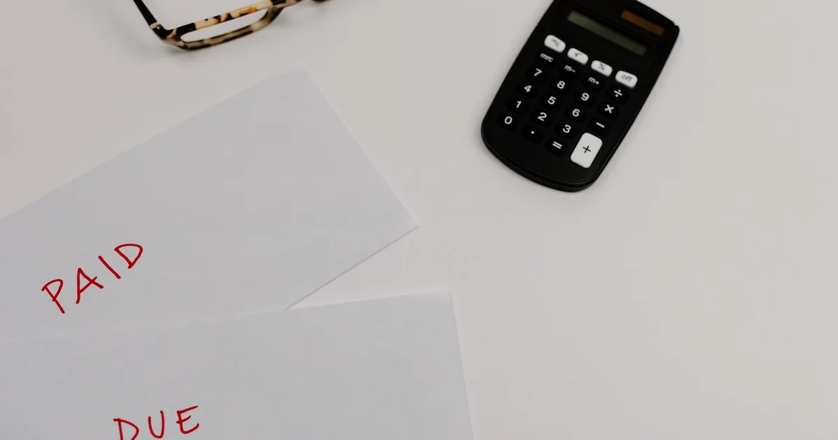 Envelopes marked paid and due next to a calculator